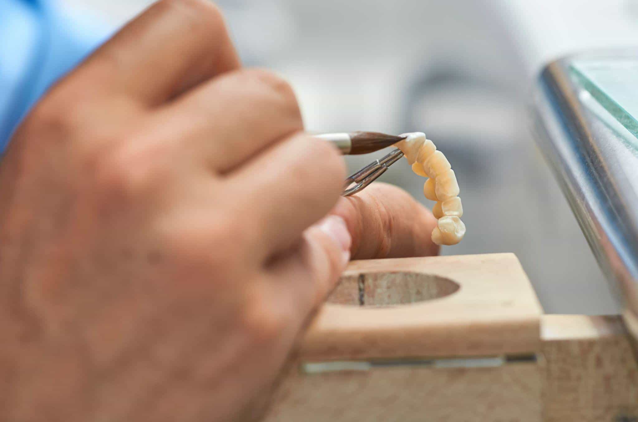 Closeup of dental technician putting ceramic to dental implants in his laboratory.